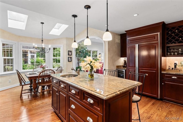 5911 Waters Edge Rd, Midlothian, VA 23112 - kitchen with paneled refrigerator, a skylight, light wood-style floors, a chandelier, and a breakfast bar