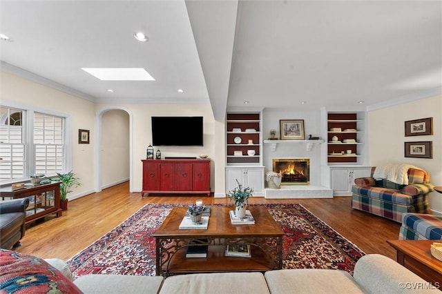 5911 Waters Edge Rd, Midlothian, VA 23112 - living area featuring a skylight, arched walkways, wood finished floors, a glass covered fireplace, and ornamental molding
