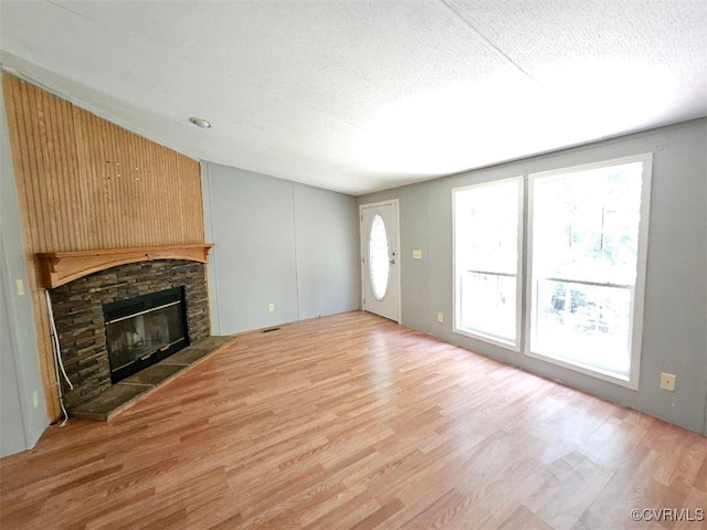 467 Oakland Rd, Farnham, VA 22460 - unfurnished living room with wood finished floors, a stone fireplace, and a textured ceiling