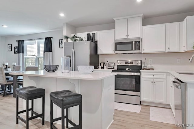 5812 Addison Gate Dr, North Chesterfield, VA 23234 - kitchen with stainless steel appliances, light wood-style flooring, a kitchen island, white cabinets, and light countertops