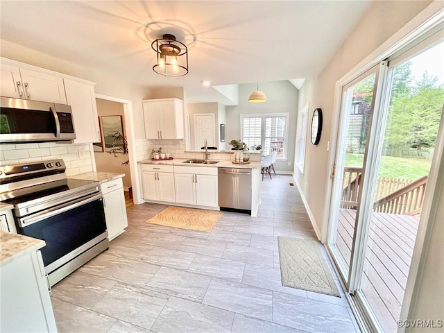 11809 Park Forest Ct, Henrico, VA 23059 - kitchen featuring appliances with stainless steel finishes, backsplash, white cabinetry, a peninsula, and hanging light fixtures