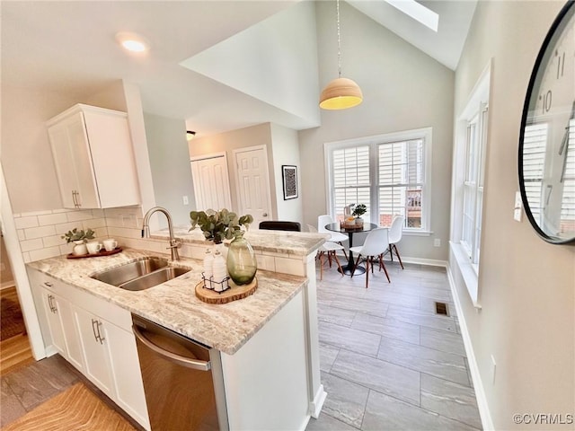 11809 Park Forest Ct, Henrico, VA 23059 - kitchen featuring stainless steel dishwasher, a skylight, a peninsula, light stone countertops, and white cabinetry