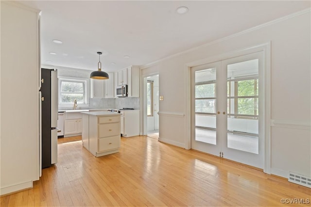 2301 Essex Rd, Henrico, VA 23228 - kitchen with appliances with stainless steel finishes, light wood finished floors, french doors, white cabinetry, and ornamental molding