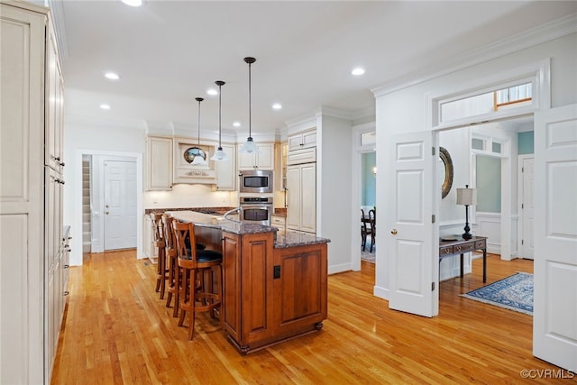 9929 Eildonway Pl, Henrico, VA 23238 - kitchen featuring built in appliances, light wood-type flooring, a kitchen breakfast bar, a center island with sink, and dark stone counters