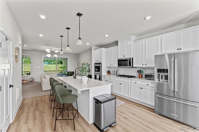 2133 Cantina Ln, Midlothian, VA 23114 - kitchen featuring appliances with stainless steel finishes, light wood finished floors, white cabinetry, light countertops, and a center island with sink