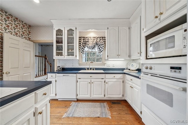 88 Holly Grv, Jamestown, VA 23185 - kitchen featuring white appliances, dark countertops, white cabinetry, light wood-style floors, and glass insert cabinets