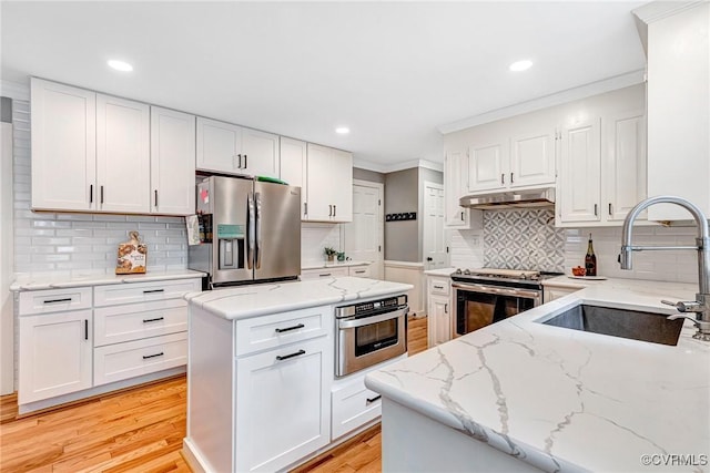 13904 Sunrise Bluff Rd, Chesterfield, VA 23112 - kitchen featuring appliances with stainless steel finishes, under cabinet range hood, light stone counters, light wood finished floors, and ornamental molding