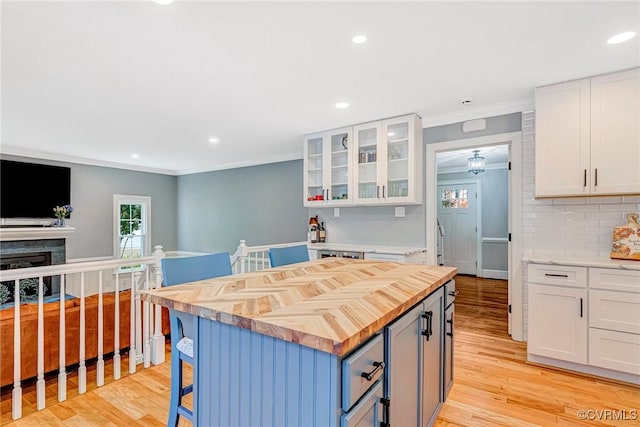 13904 Sunrise Bluff Rd, Chesterfield, VA 23112 - kitchen featuring wood counters, a breakfast bar area, white cabinets, ornamental molding, and light wood finished floors