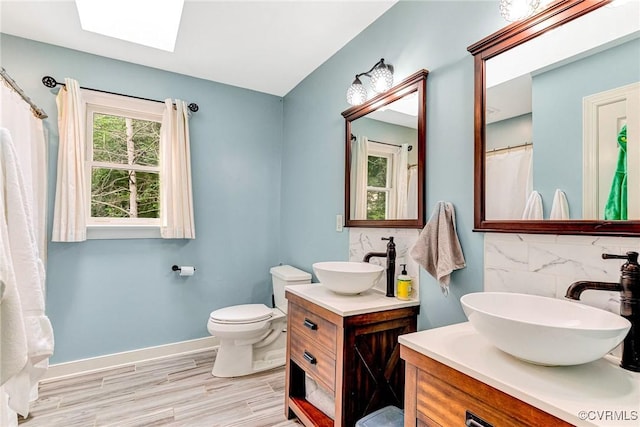 13904 Sunrise Bluff Rd, Chesterfield, VA 23112 - bathroom with a skylight, decorative backsplash, wood finished floors, and two vanities