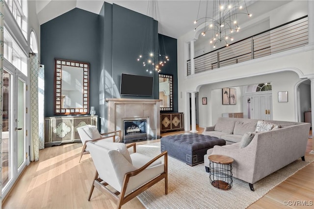 3808 Solebury Pl, Midlothian, VA 23113 - living room featuring a towering ceiling, arched walkways, wood finished floors, a tile fireplace, and a chandelier
