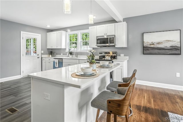 21405 Chesterfield Ave, Chesterfield, VA 23803 - kitchen featuring appliances with stainless steel finishes, a breakfast bar area, light countertops, dark wood-style flooring, and recessed lighting