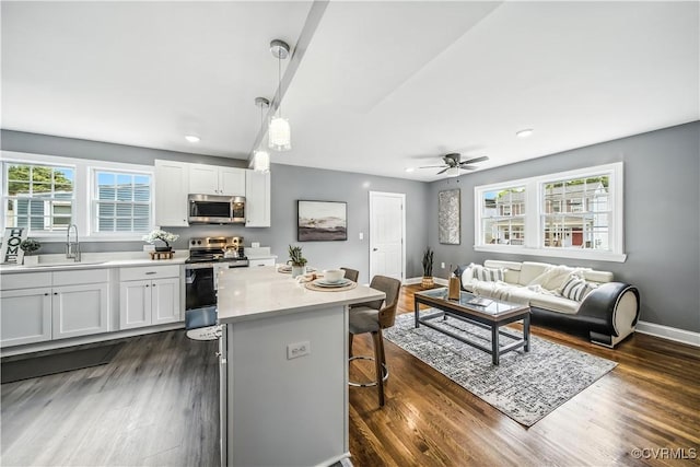 21405 Chesterfield Ave, Chesterfield, VA 23803 - kitchen with stainless steel appliances, a breakfast bar, dark wood-style flooring, light countertops, and a ceiling fan