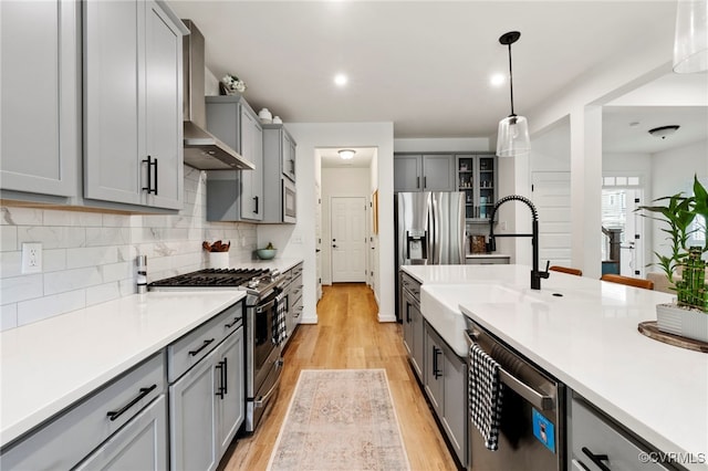 18517 Palisades Rdg, Moseley, VA 23120 - kitchen featuring stainless steel appliances, gray cabinetry, wall chimney exhaust hood, decorative backsplash, and light wood-style flooring