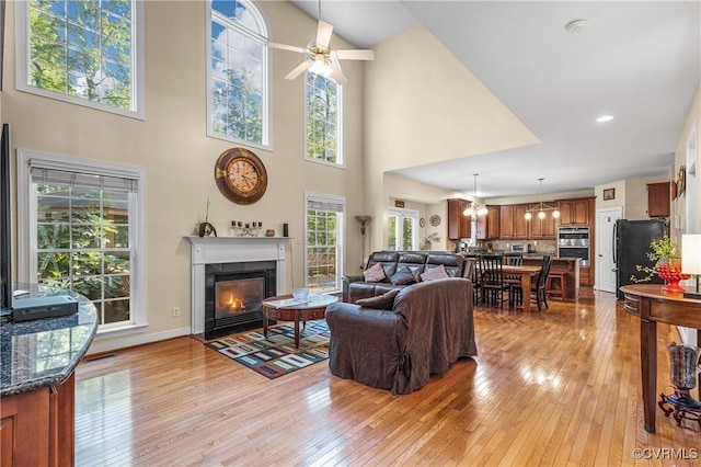3541 Kings Farm Dr, Midlothian, VA 23113 - living area featuring light wood-style floors, a fireplace with flush hearth, a ceiling fan, a high ceiling, and a chandelier