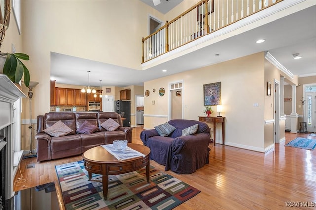 3541 Kings Farm Dr, Midlothian, VA 23113 - living area with light wood-type flooring, a high ceiling, a chandelier, decorative columns, and ornamental molding