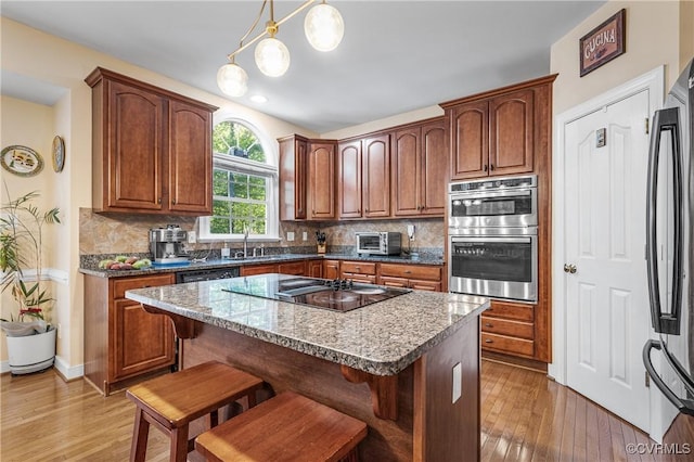 3541 Kings Farm Dr, Midlothian, VA 23113 - kitchen with stainless steel double oven, fridge, black electric stovetop, a kitchen bar, and decorative backsplash