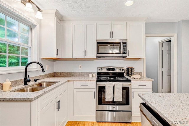 9118 Epps Rd, Mechanicsville, VA 23111 - kitchen featuring appliances with stainless steel finishes, white cabinets, light stone countertops, and light wood finished floors