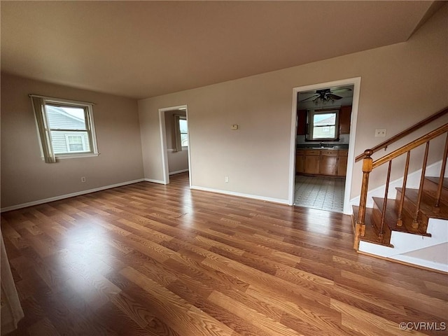spare room with plenty of natural light, stairs, and wood finished floors