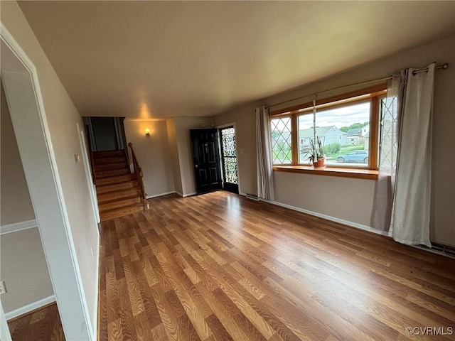 unfurnished room with wood finished floors and stairs