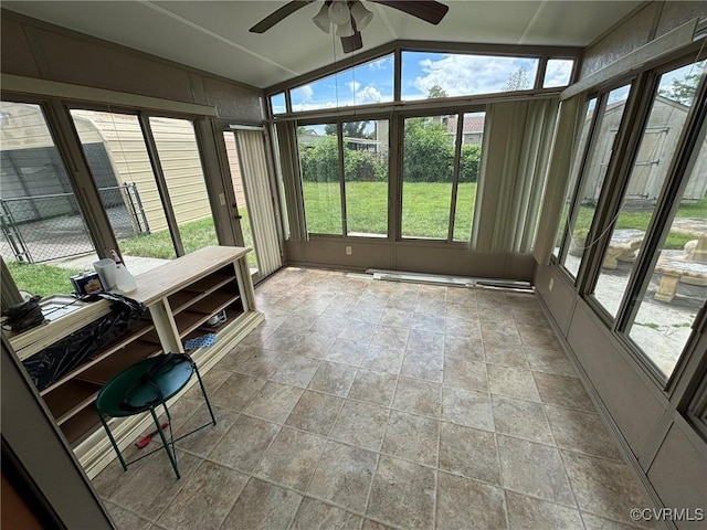 sunroom / solarium featuring vaulted ceiling, ceiling fan, and stone finish floors