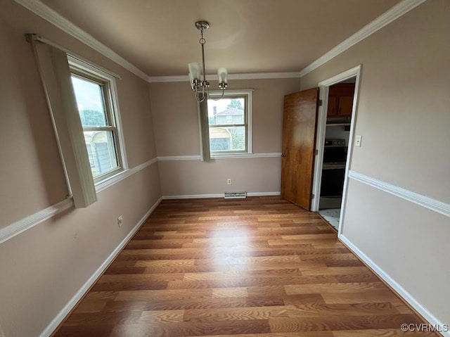 unfurnished dining area featuring light wood-type flooring, a chandelier, and ornamental molding