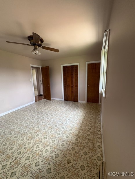 unfurnished bedroom with ceiling fan and multiple closets