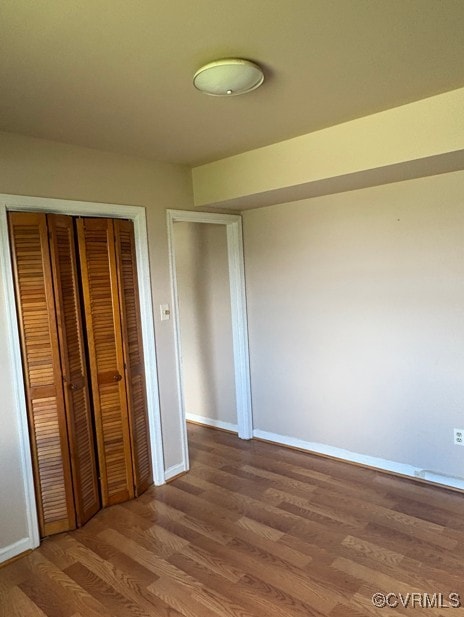 unfurnished bedroom with wood finished floors and a closet