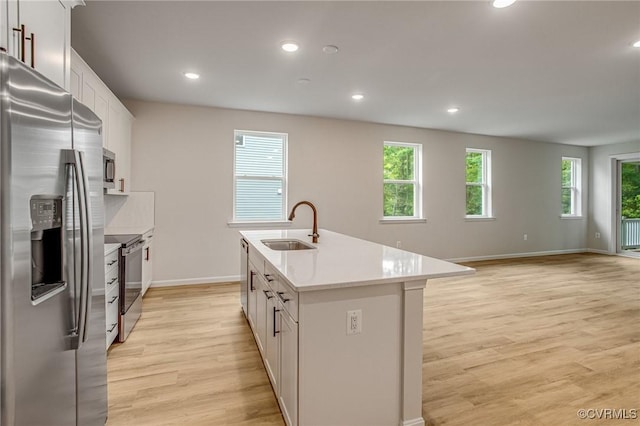 7082 Braxton Ct, Ladysmith, VA 22546 - kitchen with appliances with stainless steel finishes, light wood-style floors, a kitchen island with sink, recessed lighting, and light countertops