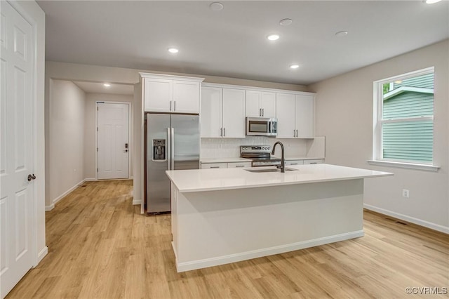 7082 Braxton Ct, Ladysmith, VA 22546 - kitchen with appliances with stainless steel finishes, light wood-type flooring, a kitchen island with sink, decorative backsplash, and recessed lighting