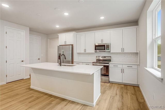 7082 Braxton Ct, Ladysmith, VA 22546 - kitchen featuring appliances with stainless steel finishes, light wood-type flooring, white cabinets, a kitchen island with sink, and recessed lighting