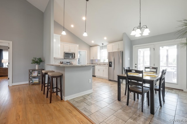 8622 Rock Cedar Rd, New Kent, VA 23124 - kitchen with stainless steel appliances, decorative backsplash, white cabinets, a peninsula, and high vaulted ceiling