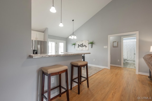 8622 Rock Cedar Rd, New Kent, VA 23124 - kitchen with stainless steel refrigerator with ice dispenser, high vaulted ceiling, white cabinets, light wood-type flooring, and a kitchen bar
