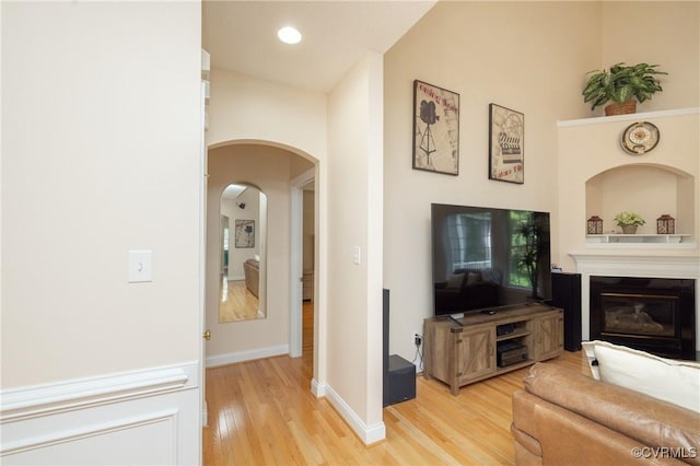 4837 Glenmorgan Ct, Chester, VA 23831 - living area featuring light wood-type flooring, arched walkways, a glass covered fireplace, and recessed lighting