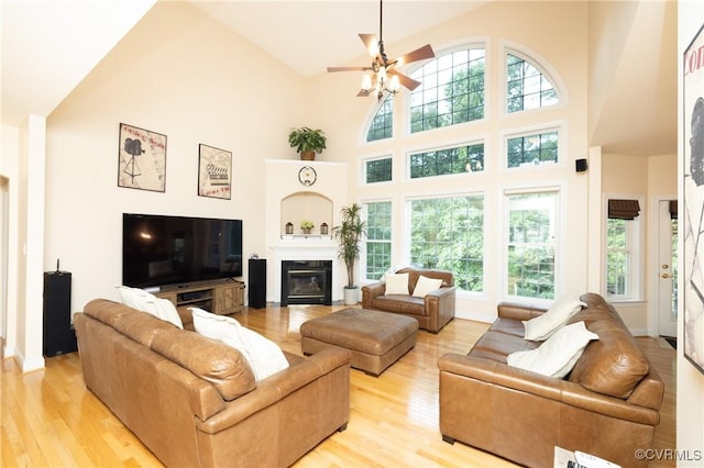 4837 Glenmorgan Ct, Chester, VA 23831 - living room featuring a towering ceiling, light wood-type flooring, a ceiling fan, and a glass covered fireplace