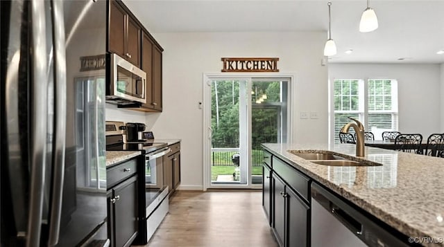 7750 Leeds Castle Ln, New Kent, VA 23124 - kitchen with stainless steel appliances, light wood finished floors, decorative light fixtures, dark brown cabinets, and light stone counters