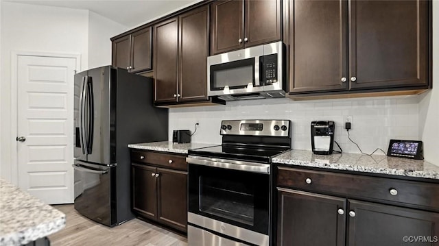 7750 Leeds Castle Ln, New Kent, VA 23124 - kitchen featuring appliances with stainless steel finishes, backsplash, dark brown cabinets, light stone countertops, and light wood-style flooring