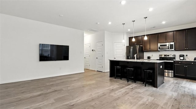 7750 Leeds Castle Ln, New Kent, VA 23124 - kitchen featuring stainless steel appliances, a breakfast bar area, a center island with sink, light wood-style floors, and recessed lighting