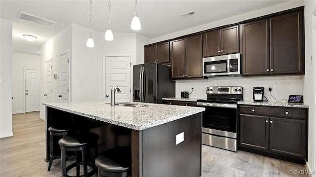 7750 Leeds Castle Ln, New Kent, VA 23124 - kitchen featuring appliances with stainless steel finishes, light wood finished floors, a breakfast bar, and dark brown cabinets