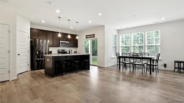 7750 Leeds Castle Ln, New Kent, VA 23124 - kitchen featuring fridge with ice dispenser, stainless steel microwave, an island with sink, light countertops, and dark brown cabinetry
