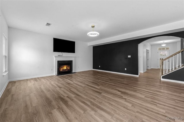10485 Eagle Ct, Prince George, VA 23860 - unfurnished living room featuring arched walkways, a glass covered fireplace, wood finished floors, and stairway