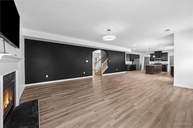 10485 Eagle Ct, Prince George, VA 23860 - unfurnished living room with a premium fireplace, light wood finished floors, arched walkways, stairs, and recessed lighting