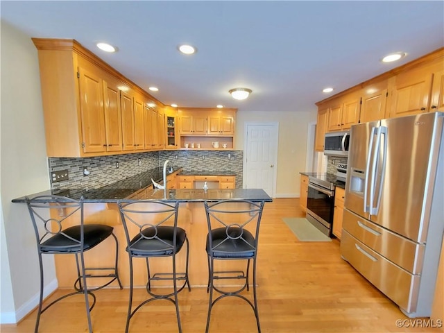 231 White Sand Ct, Colonial Heights, VA 23834 - kitchen featuring stainless steel appliances, a peninsula, tasteful backsplash, light wood-style flooring, and a kitchen bar