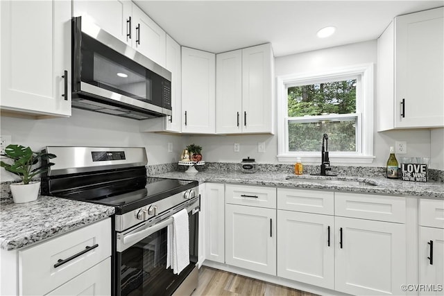 22805 Carson Rd, Carson, VA 23841 - kitchen featuring appliances with stainless steel finishes, white cabinetry, light wood-style flooring, and light stone counters