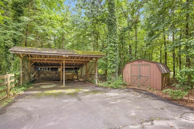 13241 Bailey Bridge Rd, North Chesterfield, VA 23112 - view of parking / parking lot featuring a carport, a shed, asphalt driveway, and a wooded view