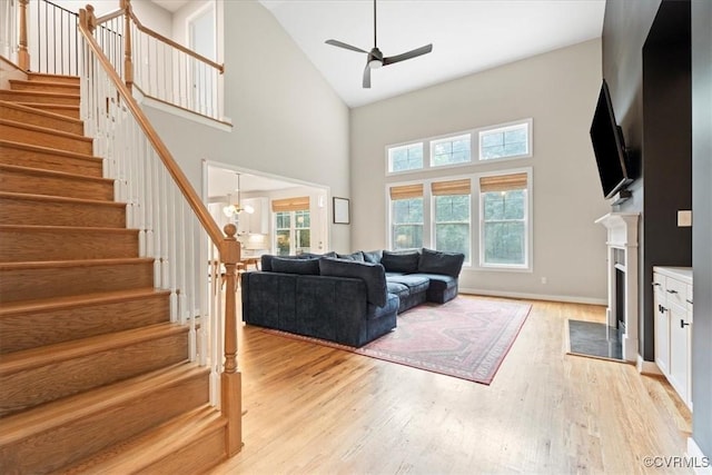 1450 Palmore Rd, Powhatan, VA 23139 - living room featuring high vaulted ceiling, ceiling fan, stairway, a fireplace, and light wood-type flooring