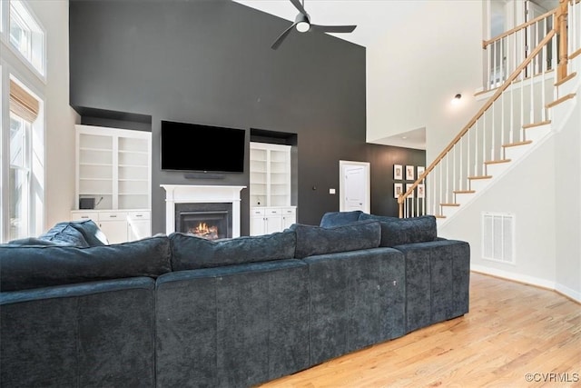 1450 Palmore Rd, Powhatan, VA 23139 - living room featuring a high ceiling, a ceiling fan, a lit fireplace, stairs, and wood finished floors