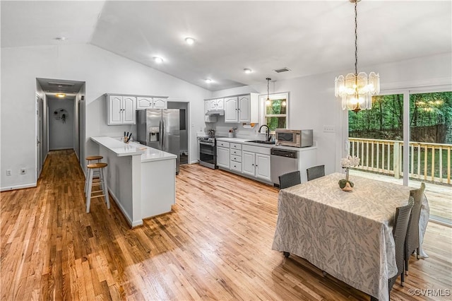 4508 Philips Path, Kents Store, VA 23084 - kitchen featuring appliances with stainless steel finishes, a kitchen bar, a peninsula, vaulted ceiling, and light wood-style flooring