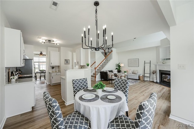 915 Jamerson Ln, Glen Allen, VA 23059 - dining room with dark wood-style flooring, stairs, a chandelier, ceiling fan, and a glass covered fireplace