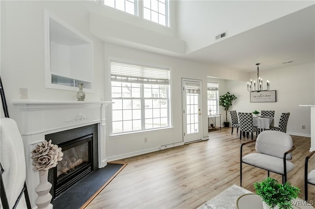 915 Jamerson Ln, Glen Allen, VA 23059 - living area featuring light wood-type flooring, a glass covered fireplace, a chandelier, and a towering ceiling