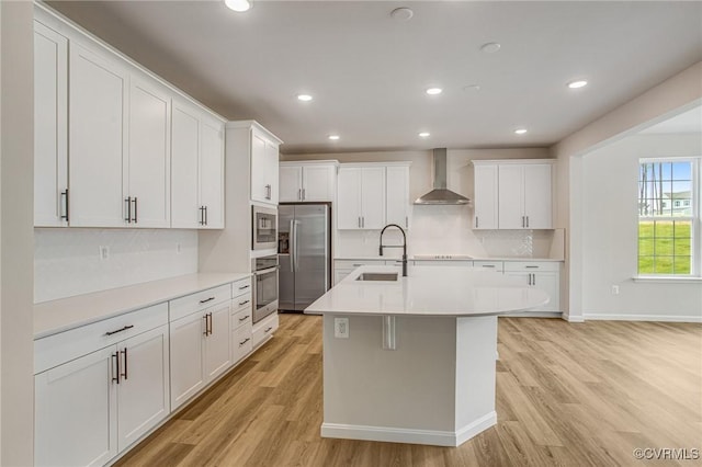 7127 Braxton Ct, Ladysmith, VA 22546 - kitchen with stainless steel appliances, wall chimney exhaust hood, decorative backsplash, light wood-style floors, and light countertops